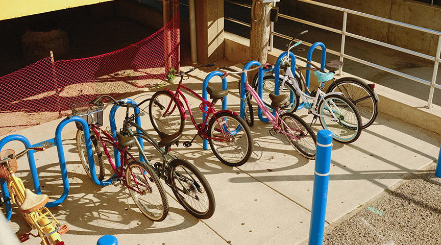 Bright blue loop bike racks installed outside a commercial building, providing durable and visible outdoor bicycle parking for customers and employees.